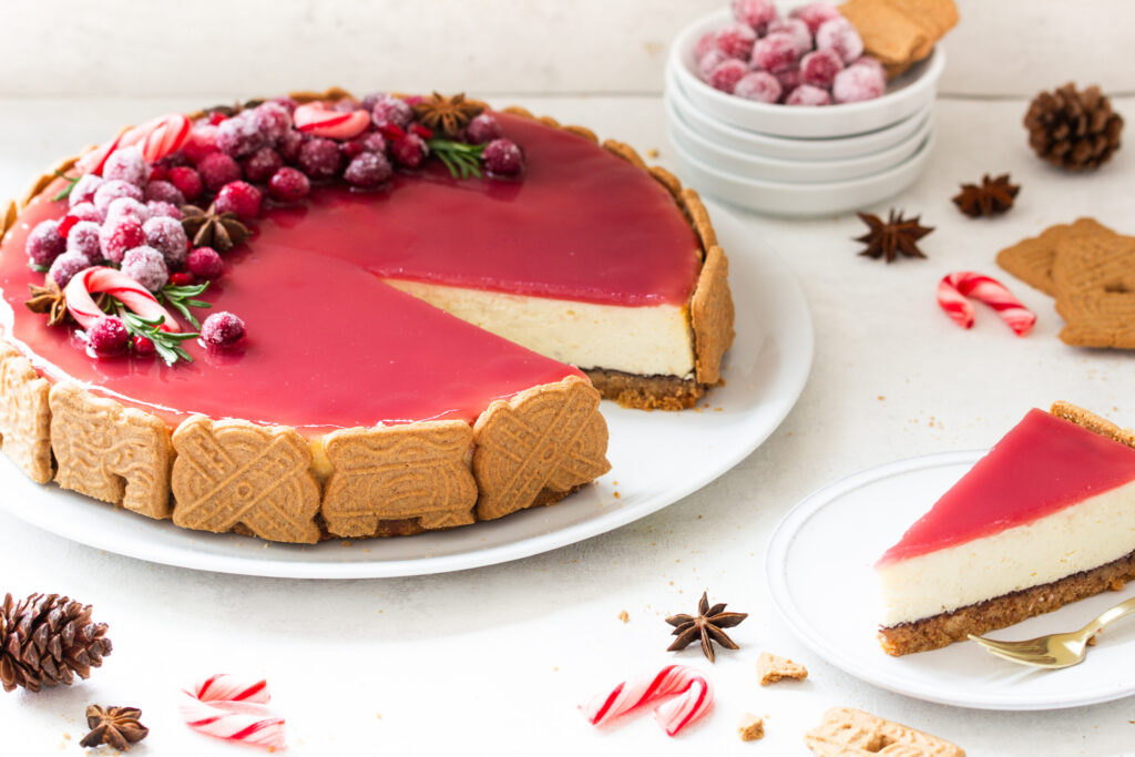 Spekulatius Cheesecake mit einem Granatapfelspiegel und einem opulenten Fruchttopping aus kandierten Cranberries, Granatapfelkernen, Sternanis und Rosmarin, seitlich fotografiert
