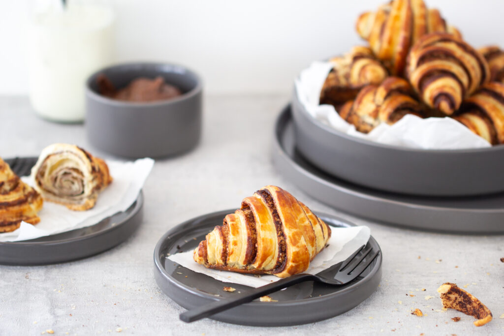 Ein Schoko Croissant mit Nutella / Nuss-Nougat-Creme auf einem Teller.