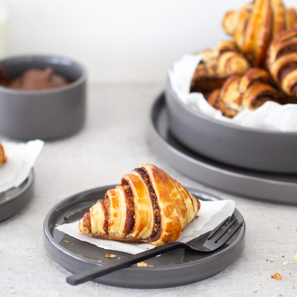 Ein Schoko Croissant mit Nutella / Nuss-Nougat-Creme auf einem Teller.