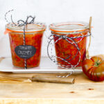 Zwei Gläser selbstgemachtes Tomaten-Chutney auf einem Teller