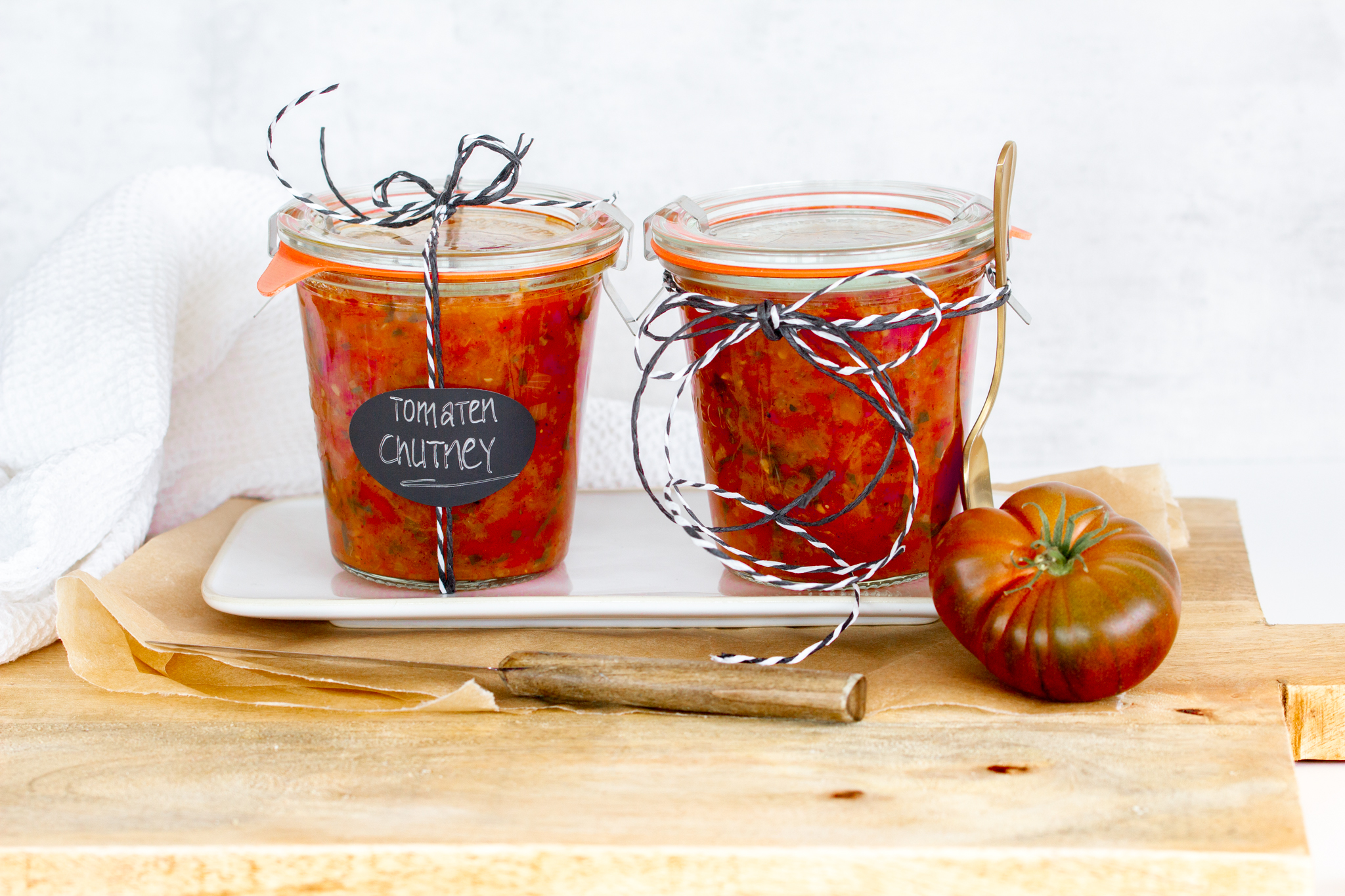Zwei Gläser selbstgemachtes Tomaten-Chutney auf einem Teller
