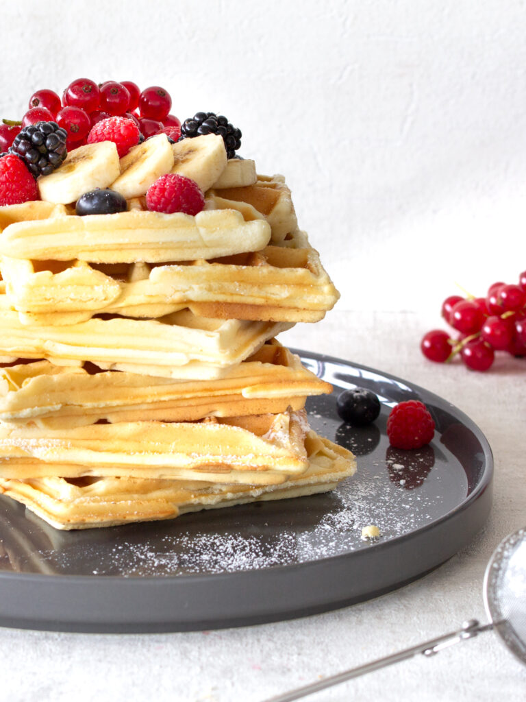Großer Stapel belgische Waffeln mit Beeren-Topping auf einem Teller