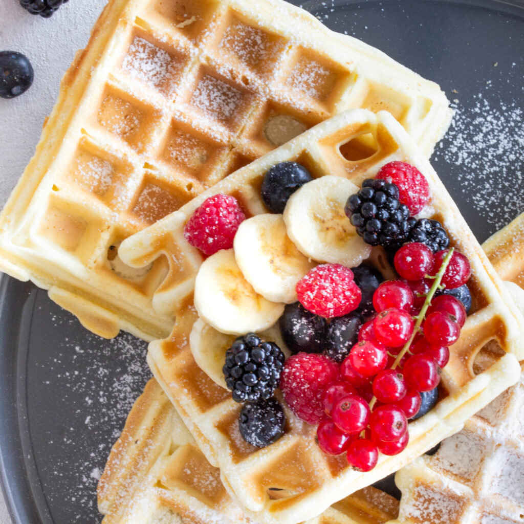 Belgische Waffeln mit Beeren-Topping und Puderzucker auf einem Teller