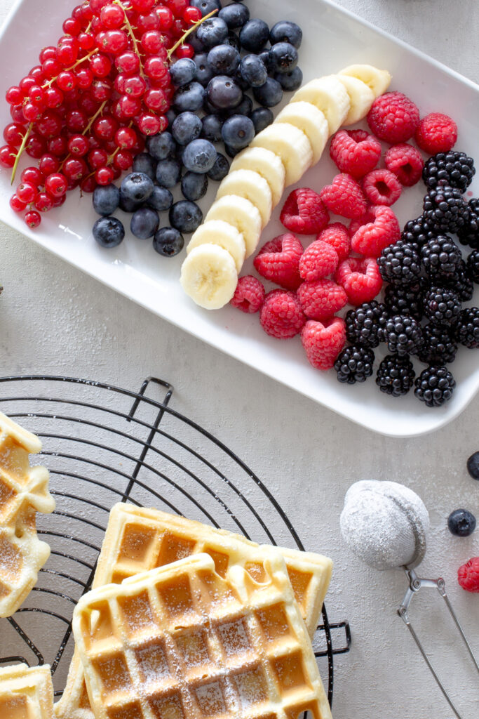 Zutaten für Beeren-Topping, nebenan liegen frisch gebackene belgische Waffeln