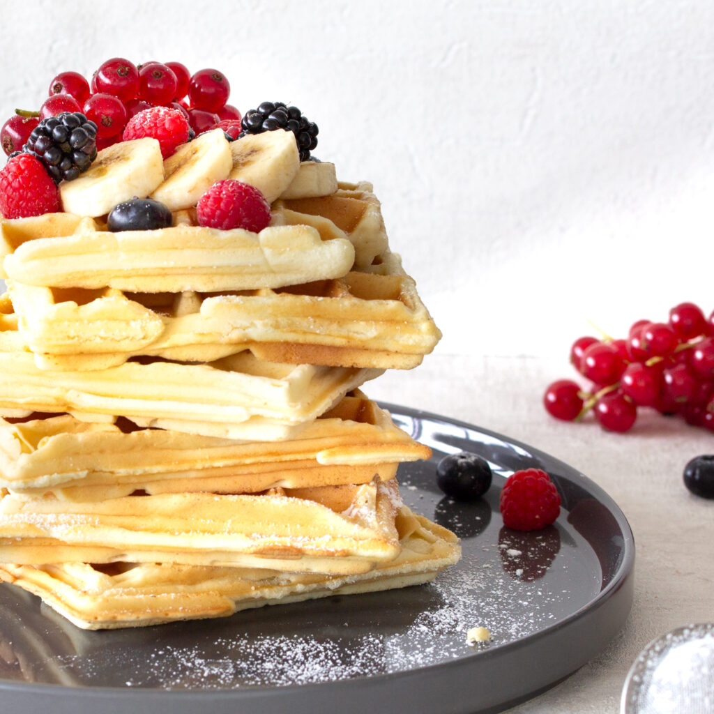 Großer Stapel belgische Waffeln mit Beeren-Topping auf einem Teller